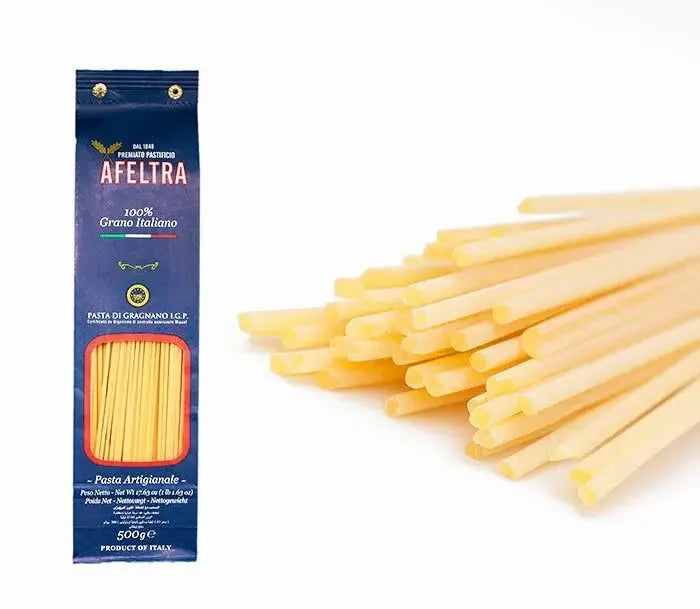 500g package of Afeltra spaghetti alla chitarra pasta made with 100% Italian wheat beside uncooked square-shaped spaghetti strands
