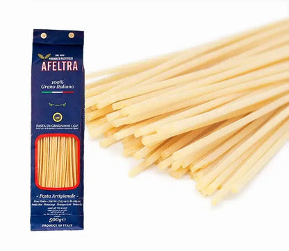 A blue package of Afeltra Bucatini pasta with 100% Italian wheat and uncooked thick hollow pasta strands beside it