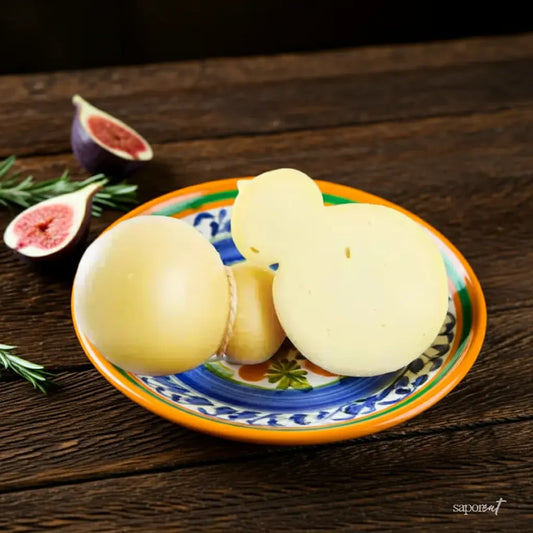 Caciocavallo cheese on a colorful ceramic plate with fresh sliced figs and rosemary on wooden table